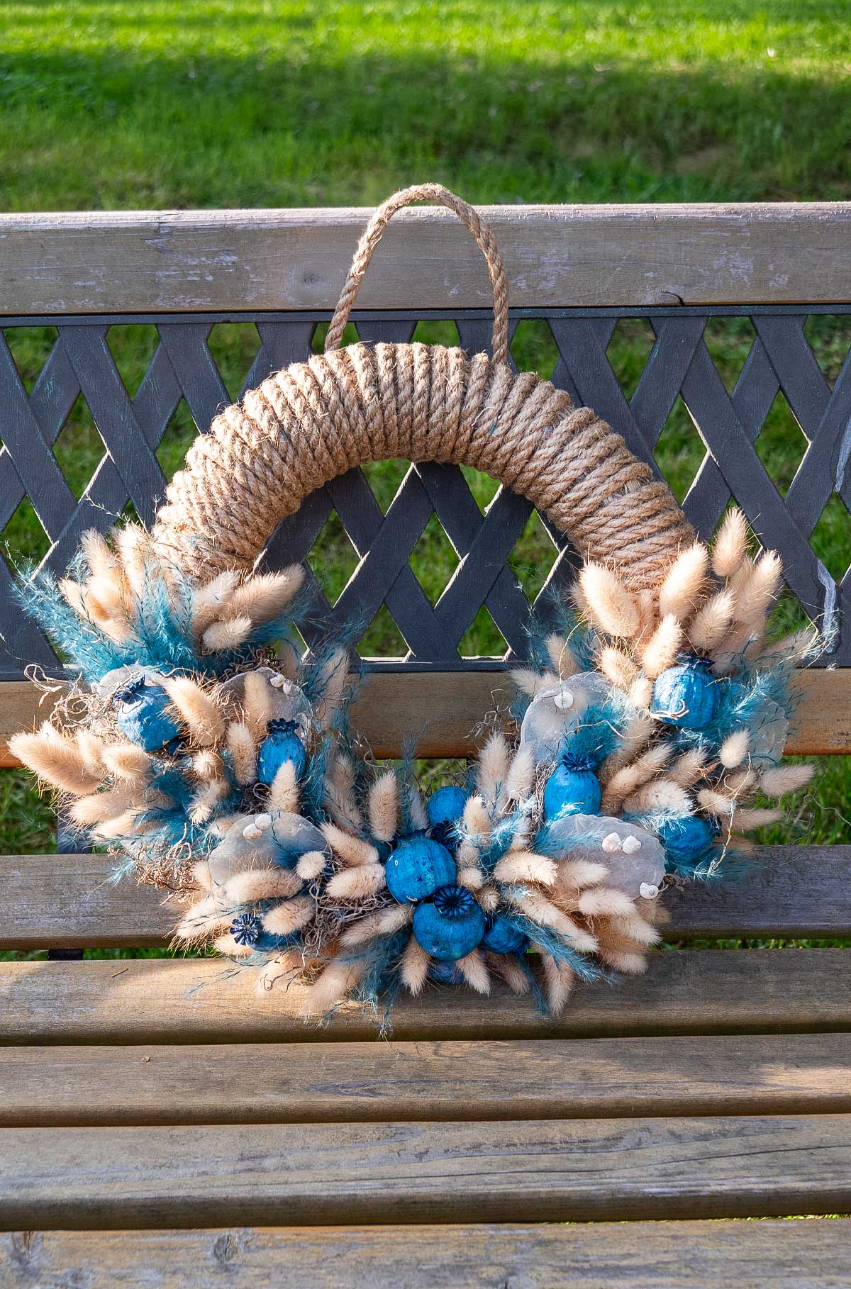 Trockenblumenkranz 'Blue Sea' in beruhigenden Blautönen, umwickelt mit Juteschnur, gegen eine weiße Kulisse – dekogreen.de